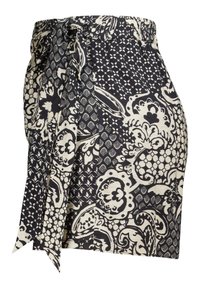 Jupe portefeuille en tissu léger, présentant un motif floral et géométrique noir et crème, avec un lien à la taille pour la fermeture.