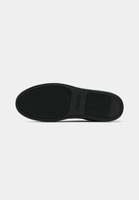 Sole de cauciuc negru cu un model texturat, având un logo. Margini netede cu un călcâi ușor ridicat și pattern-uri detaliate pentru tracțiune.