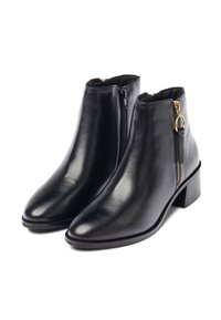 Botas de tobillo de cuero negro con un acabado suave, punta afilada y detalles de cremallera dorada. Tacón bajo cuadrado para mayor estabilidad.