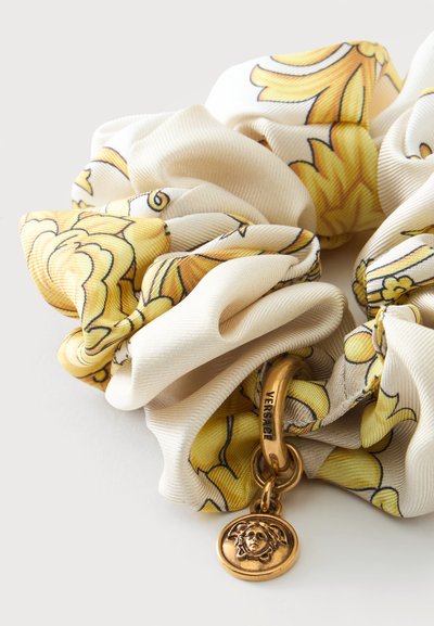 Chouchou en tissu à motifs crème et jaune avec un charme Méduse doré et une bague gravée "Versace".