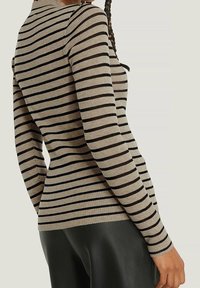 Beige ribbattu pitkähihainen paita mustilla vaaka-aitoilla, jossa on korkea kaula-aukko ja tiivis siluetti.