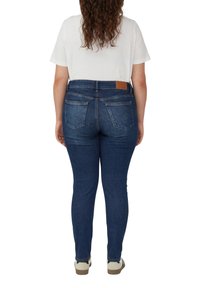 Strakke jeans van donkerblauwe denim met een gladde textuur, gekenmerkt door een bruin leren label aan de achterkant en twee achterzakken met accentstiksel.