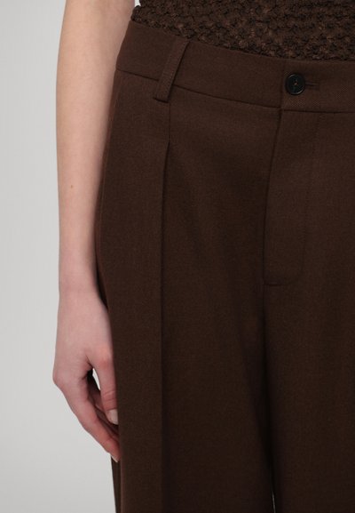 Brown tailored trousers with a textured fabric, featuring a front pleat, belt loops, and a single black button closure.