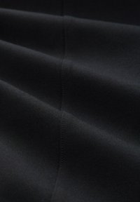 Zwart stof met een gladde, matte textuur, met subtiele naden en plooien, weergegeven vanuit een close-up perspectief.