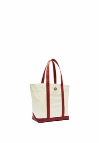 Sac en toile de couleur crème avec des accents rouges. Il possède deux poignées en tissu rouge et une base rouge. Un logo circulaire est centré à l'avant.