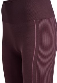 Legginsy w kolorze burgundowym, z wysokim stanem, z teksturowanym żebrowaniem i różowymi lamówkami po bokach, wykonane z elastycznego, miękkiego materiału.