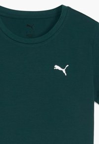 Camiseta de algodón de color verde oscuro con un escote redondo y un pequeño logo blanco de Puma en el lado izquierdo del pecho. Textura suave con un ajuste clásico.