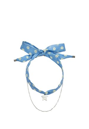 Niebieska opaska materiałowa w białe kropki, związana w kokardę, z srebrnym zawieszką w kształcie gwiazdy z napisem "LUCKY CHARM" i cienkim srebrnym łańcuszkiem.