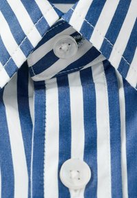 Cuello de camisa con rayas verticales azules y blancas, con dos botones blancos abrochados a través de ojales cosidos.