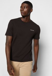 Zwarte katoenen t-shirt met korte mouwen en een ronde halslijn, voorzien van een wit 'Calvin Klein' logo geborduurd op de borst.
