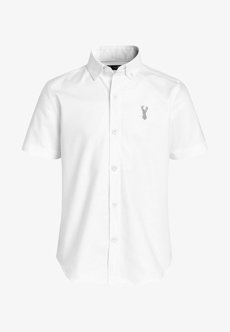 Chemise blanche à manches courtes avec des boutons sur le devant, col boutonné et un petit logo de tête de cerf gris sur la poitrine gauche.