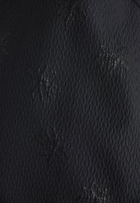 Black textured fabric featuring an embossed floral pattern, with shiny detailing on the flowers, creating a subtle contrast against the material.