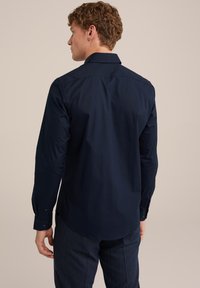 Chemise à manches longues bleu marine avec un col, des poignets à bouton et un tissu en mélange de coton lisse. Coupe ajustée et ourlet droit au dos.