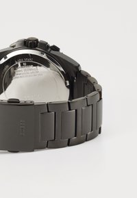 Mörk rostfritt stål armbandsur med länkbandsarmband, utrustad med en svart urtavla och kronograffunktioner. Rund boett med en texturerad krona.