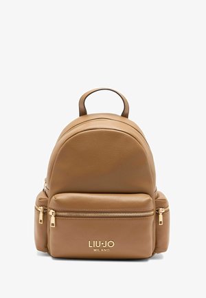 Zaino in pelle color tan con forma arrotondata, dotato di due cerniere sulla tasca anteriore, dettagli in metallo dorato e manico superiore.