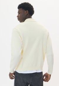 Sweatshirt galben deschis cu guler, mâneci lungi și o croială lejeră. Dispune de manșete ribbate și o linie de tiv dreaptă.