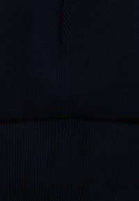 Berretto a maglia in blu navy scuro, caratterizzato da una texture a coste e un risvolto pieghevole. Finitura liscia senza loghi o fantasie visibili.
