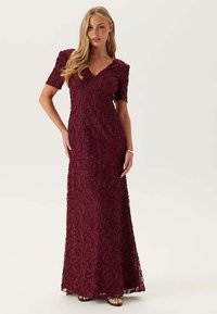 Burgundy spetsaftonklänning med korta ärmar, V-ringning och lång kjol med blommönster och en strukturerad yta.