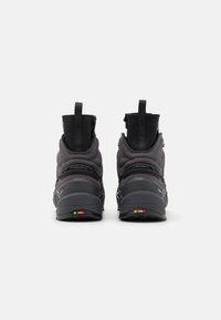 Svarte høye sneakers med teksturert stoff, polstret krage og bakre løkke; en fargerik aksent på sålen gir detaljer.