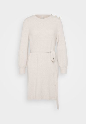 Bež neopränni kleit ümmarguse kaelusega, pikkade õhkuvaid varrukatega, talje sidemega ja külgservaga. Omab dekoratiivseid nuppe õlal.