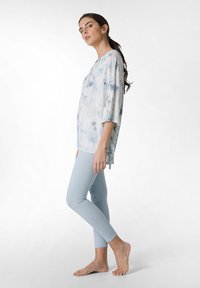 Vaaleansininen sitruunatoppi, jossa on kolme neljänneksen hihoja, yhdistettynä tiukkoihin vaaleansinisiin legginsseihin. Pehmeä kangas, rento malli, jossa on sivuhalkiot.