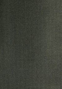 Dark green herringbone fabric with a fine zigzag pattern, exhibiting a textured surface. Material appears dense and woven.