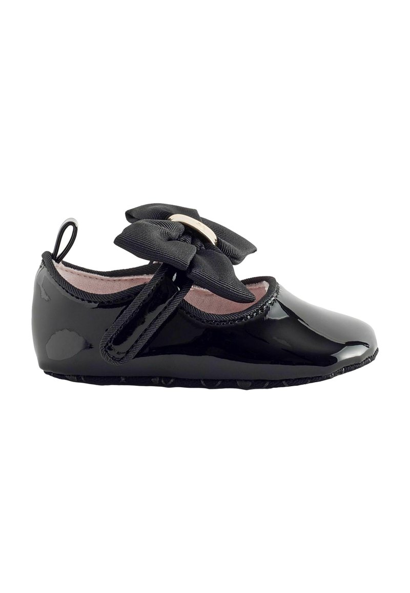 Schwarzer Lacklederschuh mit runder Zehenpartie, versehen mit einer schwarzen Satin-Schleife und einem Klettverschlussriemen. Weiches, pinkfarbenes Innenfutter, strukturiertes Sohlenprofil.