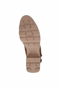 Suela marrón de zapato con una superficie texturizada, que presenta un patrón hexagonal y surcos profundos para tracción. Punta ligeramente redondeada y tacón resistente.