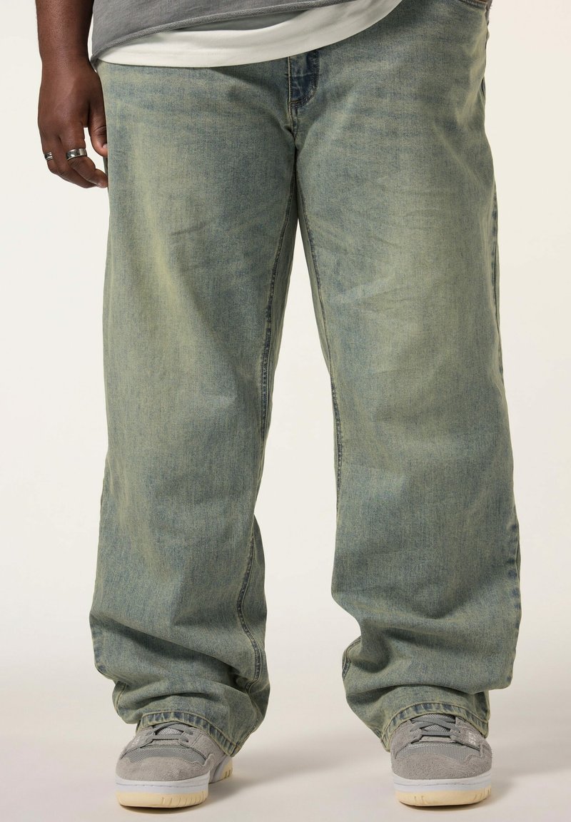Ljusblå vida jeans med en blekt look, tillverkade av denim, med en avslappnad passform och något uppvikta fållar. Bärs med grå sneakers.