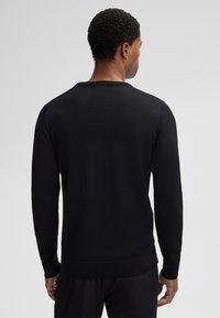 Zwarte lange mouw trui met een geribde kraag en manchetten, van achteren weergegeven, met een gladde textuur en een getailleerd ontwerp.