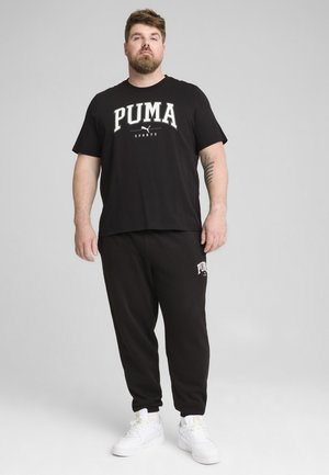 Czarny bawełniany T-shirt z grafiką "PUMA SPORTS", w zestawie z czarnymi spodniami dresowymi z logo. Całość dopełniają białe sneakersy.