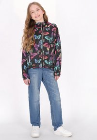 Jachetă cu glugă pe un fundal negru, împodobită cu modele colorate de fluturi în nuanțe de roz, albastru și portocaliu. Asortată cu blugi bleu deschis și adidași albi.