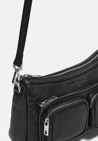 Borsa a tracolla nera in pelle con hardware in argento, dotata di più scomparti con zip e superficie testurizzata. Include una tracolla regolabile.