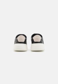 Czarne skórzane sneakersy z białą podeszwą, z różowym akcentem na pięcie oraz wytłoczonym logo z tyłu. Prosty design, zaokrąglony kształt.