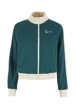 Veste zippée bleu sarcelle avec col montant, accents crème sur les épaules et les poignets, dotée d'une poche avant et d'un logo brodé sur la poitrine.