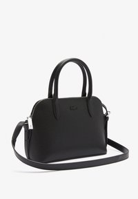 Czarna torebka wykonana z fakturowanego materiału, wyposażona w podwójne uchwyty, regulowany pasek oraz zapięcie na zamek błyskawiczny z ozdobnym srebrnym elementem.