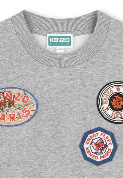 Sweatshirt en coton gris avec trois patches brodés : "KENZO PARIS" en rouge et bleu, et un motif de poisson sur un patch hexagonal.