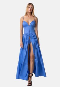 Abito maxi blu con corpetto aderente, spalline sottili e frontale con bottoni. Presenta un alto spacco e una gonna a strati, realizzato in tessuto morbido.