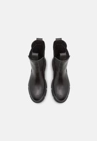 Botas de tobillo de cuero negro con textura suave, puntera redonda y tiras en la parte superior. Las suelas de goma ofrecen tracción y durabilidad.