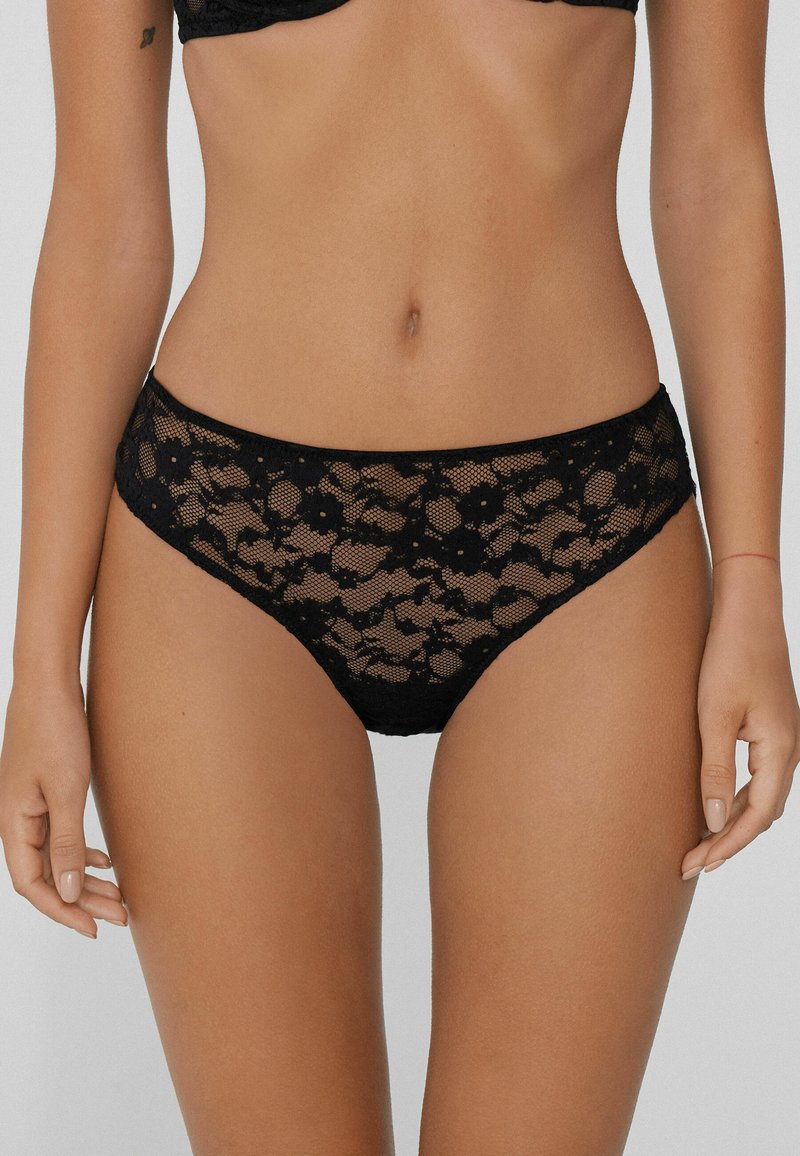Czarne koronkowe bielizna z kwiatowymi wzorami, zaprojektowana w stylu średniego podniesienia oraz o miękkiej teksturze. Szczegółowe falbany zwiększają walory wizualne.