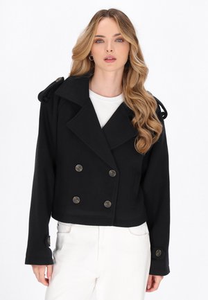 Schwarz cropped Doppelreiher-Jacke aus strukturiertem Stoff, mit großen Knöpfen und Schulterakzenten, kombiniert mit einem weißen Oberteil.