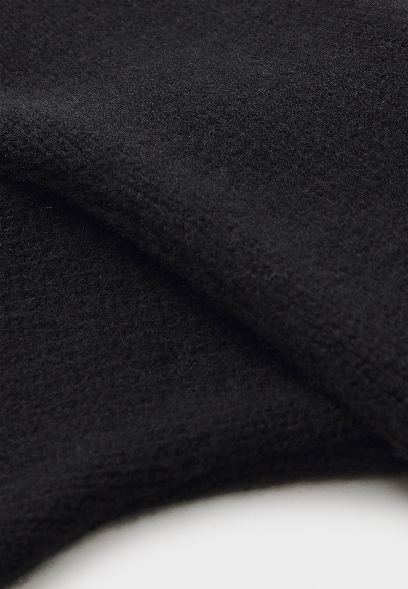 Black wool fabric, textured with a slightly fuzzy surface, draping in folds, showcasing depth and soft finish.