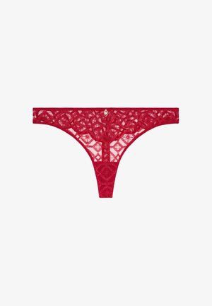 String rouge en dentelle avec des motifs floraux et géométriques complexes. Comprend une taille étroite et un petit emblème doré au centre avant.