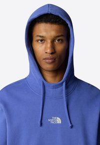 Hooded sweatshirt in light blue cotton blend. Features a front logo, drawstrings, and a relaxed fit with a ribbed neck opening.
