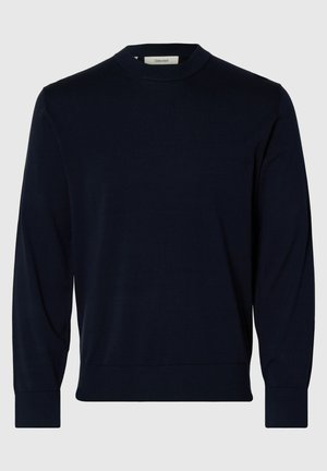 Jūros mėlynas megztinis su apvalia apykakle ir ilgomis rankovėmis, su juostuotu rankogaliu ir apačia. Minkšta tekstūra ir prigludusi siluetas.