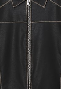 Black leather jacket with a zip closure, featuring contrast stitching along the seams and a pointed collar. Textured finish.