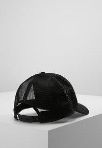Čierna baseballová čiapka so pevným predným dielom a sieťovaným zadným dielom, s uzáverom typu snapback. Textúrovaná látka s ohnutým okrajom.