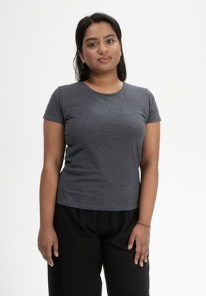 T-shirt gris à manches courtes en tissu doux et extensible, avec un col rond, associé à un pantalon noir ample. Pas de motifs ni d'accents.