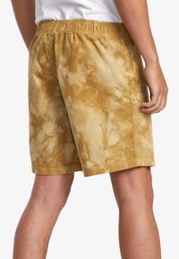 Tie-dye shorts in a mustard yellow color with a soft corduroy texture, featuring an elastic waistband and a loose fit.