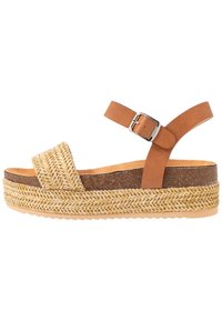 Brun läderrem sandal med vävd halmpall, platt sula och justerbar spänne. Har texturerade detaljer på ovansidan.